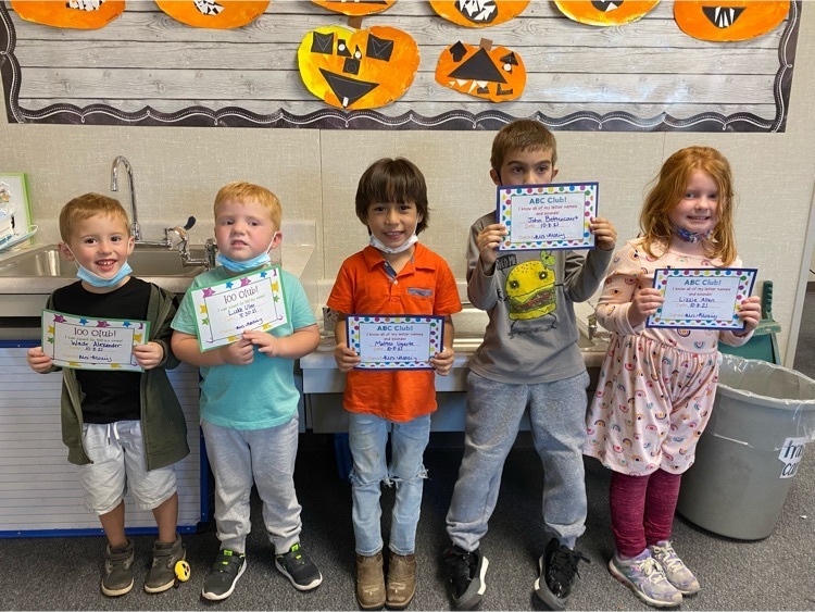 kindergarten students holding awards for joining ABC club and 100 club