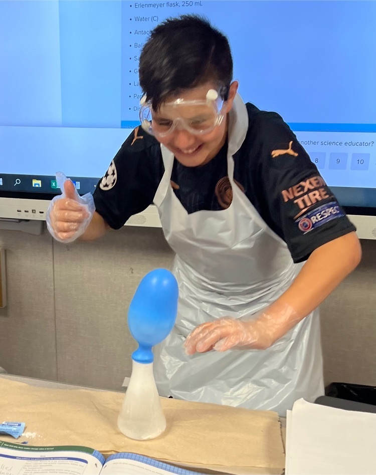 Student smiling while observing a chemical reaction 