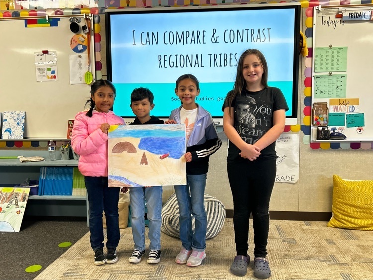 third grade students, holding a poster with a scene of the coast in colored pencil.