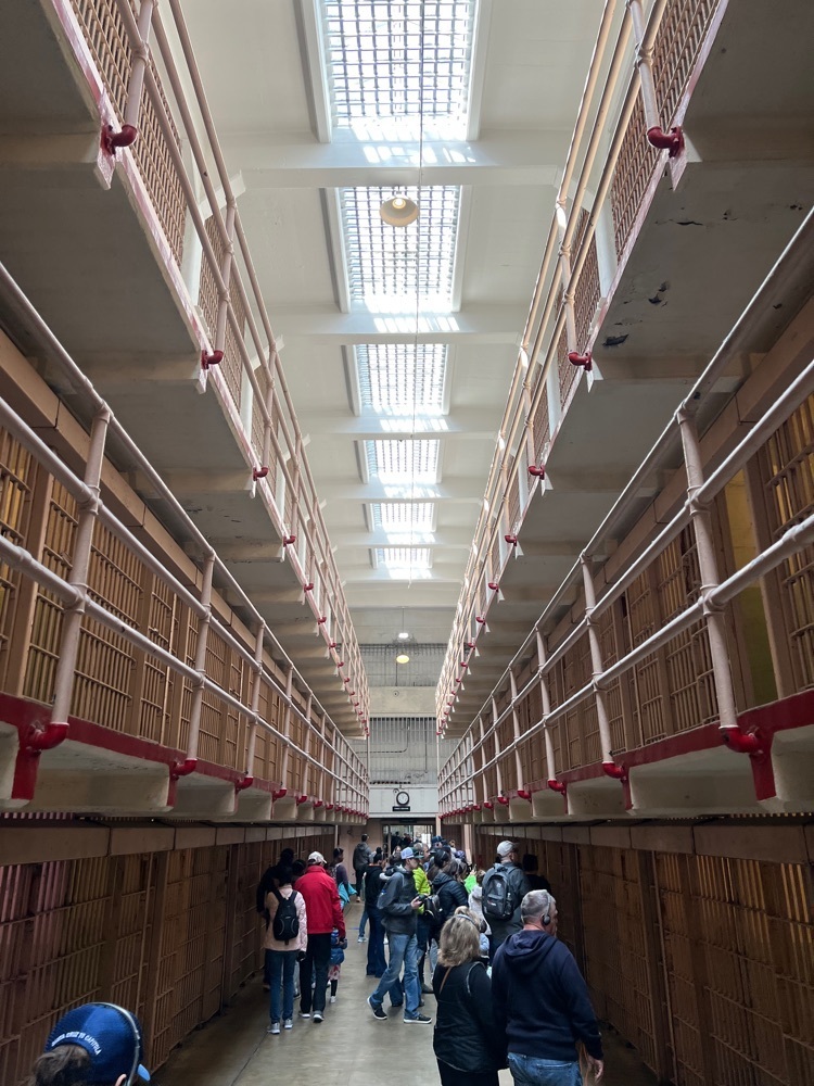 A walkway surrounded on both sides by 3 levels of prison cells 